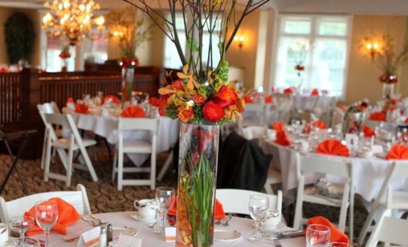 Elegant wedding reception with white linens and orange floral arrangements and napkins
