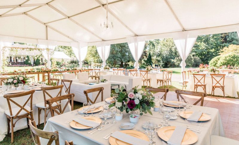 Tent wedding reception with square tables, white linens, and farm house cross backed chairs by Well Dressed Tables